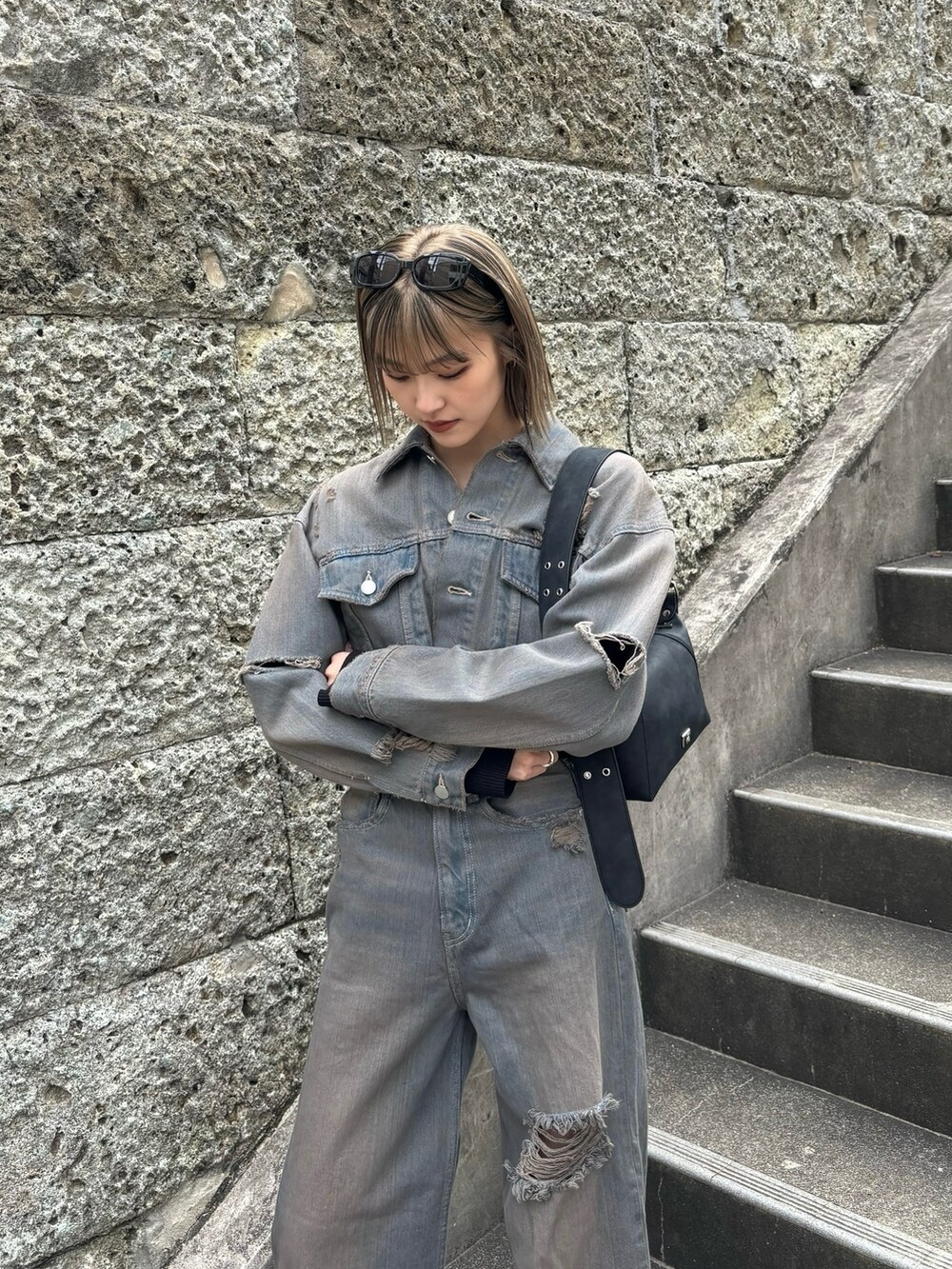 グレー系のデニムジャケット、ブラック系のニット/セーター、グレー系のデニムパンツを着用したレディースの冬コーディネートの2枚目の写真