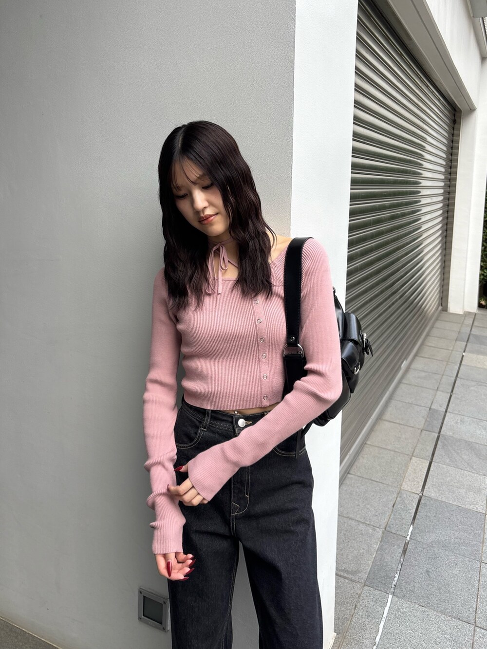 ピンク系のニット/セーター、ブルー系のデニムパンツ、ブラック系のハンドバッグを着用したレディースの冬コーディネートの2枚目の写真