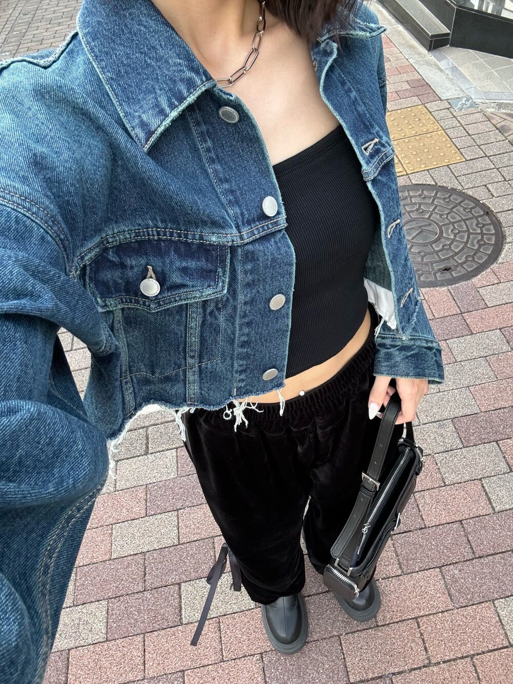 ブルー系のデニムジャケット、ブラック系のキャミソール、ブラック系のその他パンツを着用したレディースの夏コーディネートの3枚目の写真