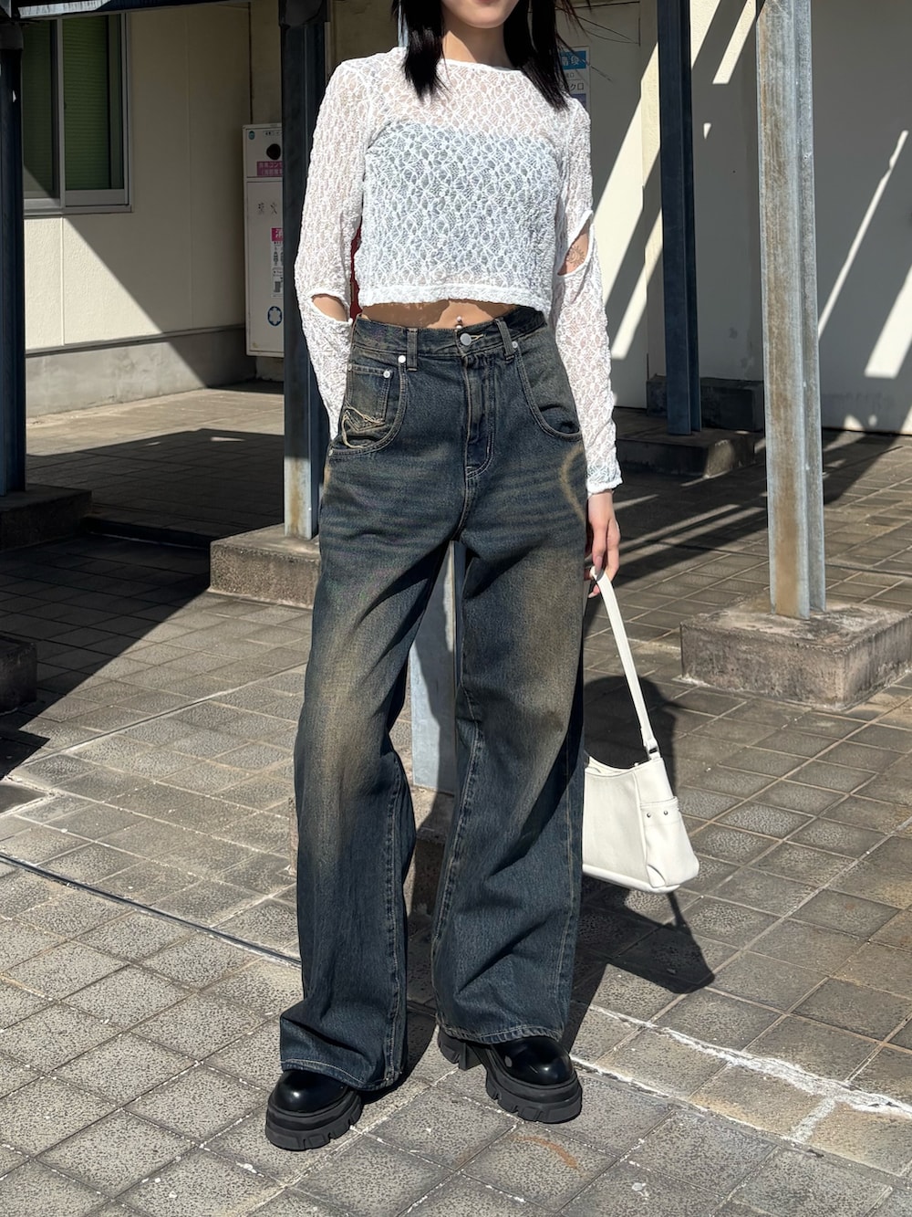 ブルー系のデニムパンツ、ブラック系のブーツ、ホワイト系のハンドバッグを着用したレディースの春コーディネートの2枚目の写真