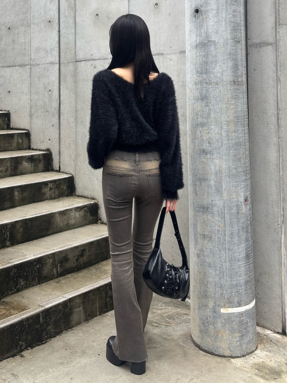 グレー系のデニムパンツ、ブラック系のブーツ、ブラック系のニット/セーターを着用したレディースの秋コーディネートの3枚目の写真