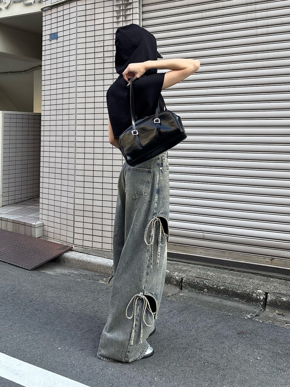 ブルー系のデニムパンツ、シルバー系のスニーカー、ブラック系のTシャツ/カットソーを着用したレディースの春コーディネートの2枚目の写真