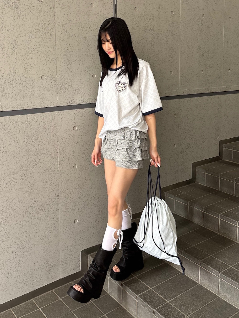 グレー系のスカート、ホワイト系のTシャツ/カットソー、ホワイト系のバックパック/リュックを着用したレディースの冬コーディネートの3枚目の写真