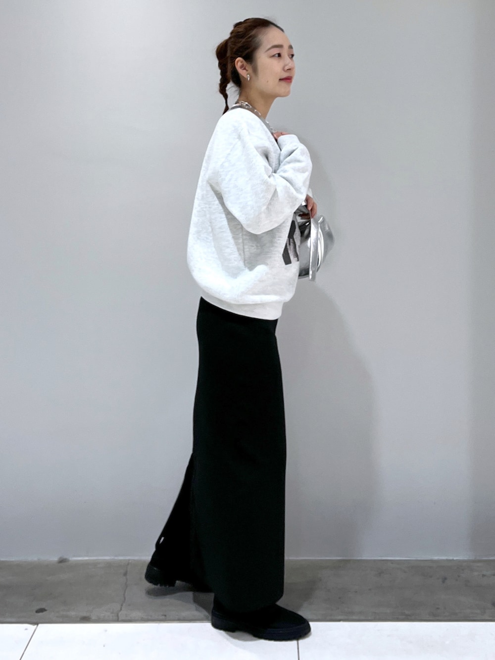 ブラック系のスカート、シルバー系のショルダーバッグ、グレー系のスウェットを着用したレディースの冬コーディネートの2枚目の写真