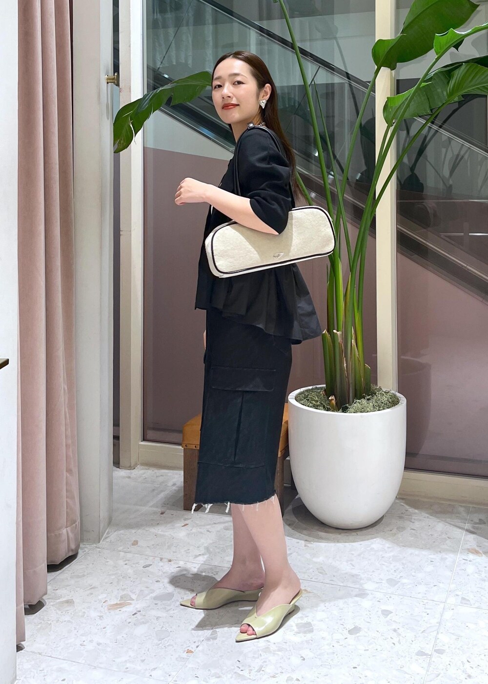 ベージュ系のサンダル、ホワイト系のボストンバッグ、ブラック系のカーディガン/ボレロを着用したレディースの春コーディネートの2枚目の写真