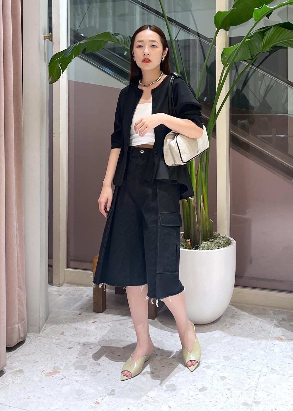 ベージュ系のサンダル、ホワイト系のボストンバッグ、ブラック系のカーディガン/ボレロを着用したレディースの春コーディネートの3枚目の写真