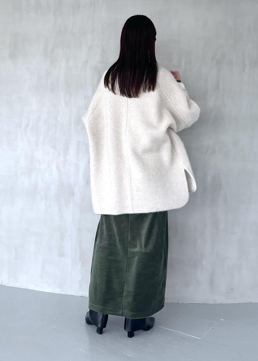 グリーン系のワンピース、ブラック系のブーツ、ホワイト系のカーディガン/ボレロを着用したレディースの秋コーディネートの3枚目の写真