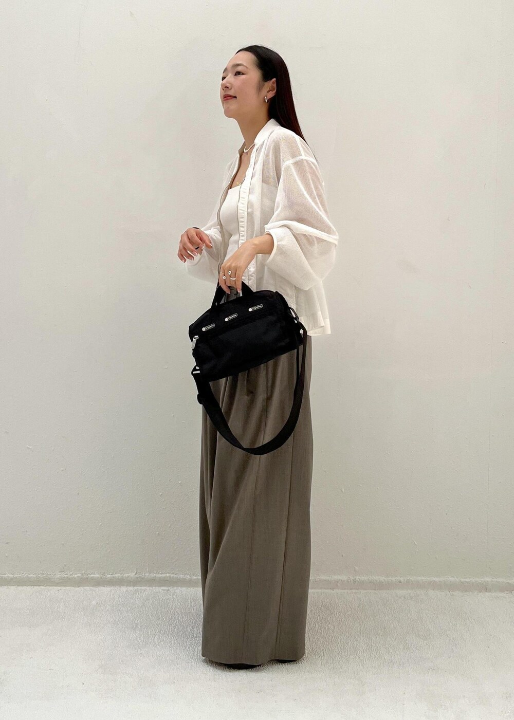 グレー系のスラックス、ホワイト系のカーディガン/ボレロを着用したレディースの春コーディネートの2枚目の写真