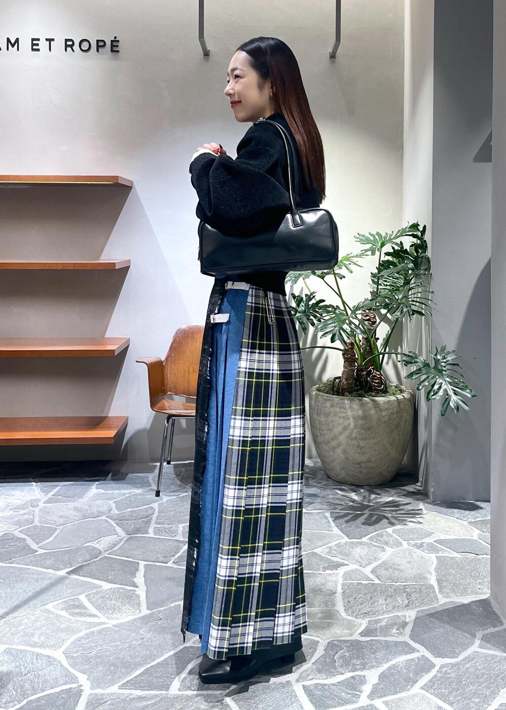 グレー系のスカート、ブラック系のブーツ、ブラック系のニット/セーターを着用したレディースの冬コーディネートの2枚目の写真