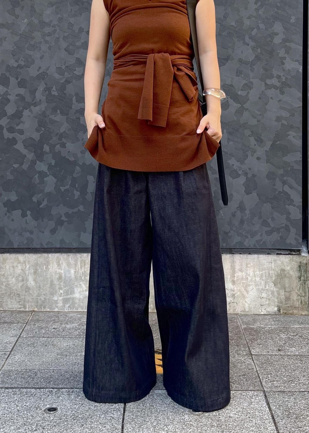 ブラウン系のニット/セーター、ブルー系のデニムパンツ、ブラック系のショルダーバッグを着用したレディースの夏コーディネートの4枚目の写真