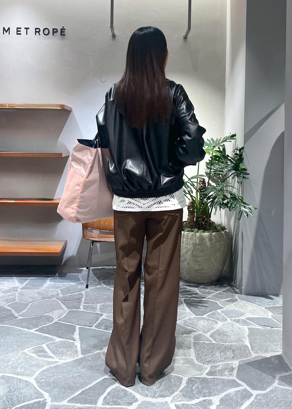 ブラック系のサンダル、ホワイト系のベスト、ブラック系のブルゾンを着用したレディースの春コーディネートの4枚目の写真