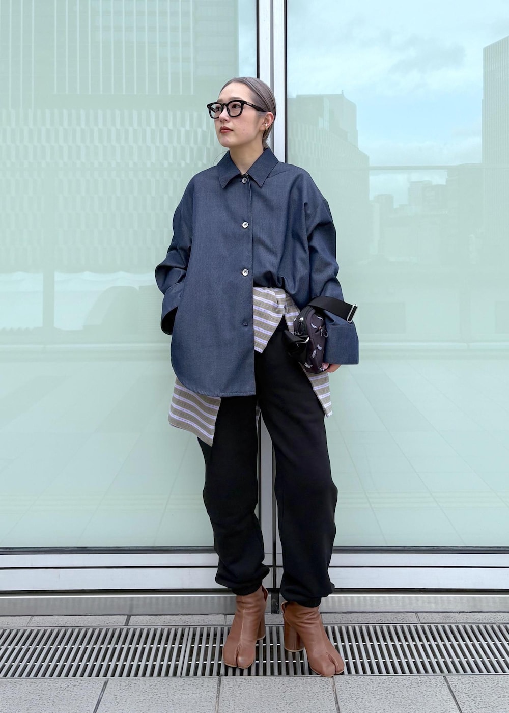 ブルー系のブルゾン、ブラック系のトートバッグ、パープル系のポロシャツを着用したレディースの冬コーディネートの2枚目の写真