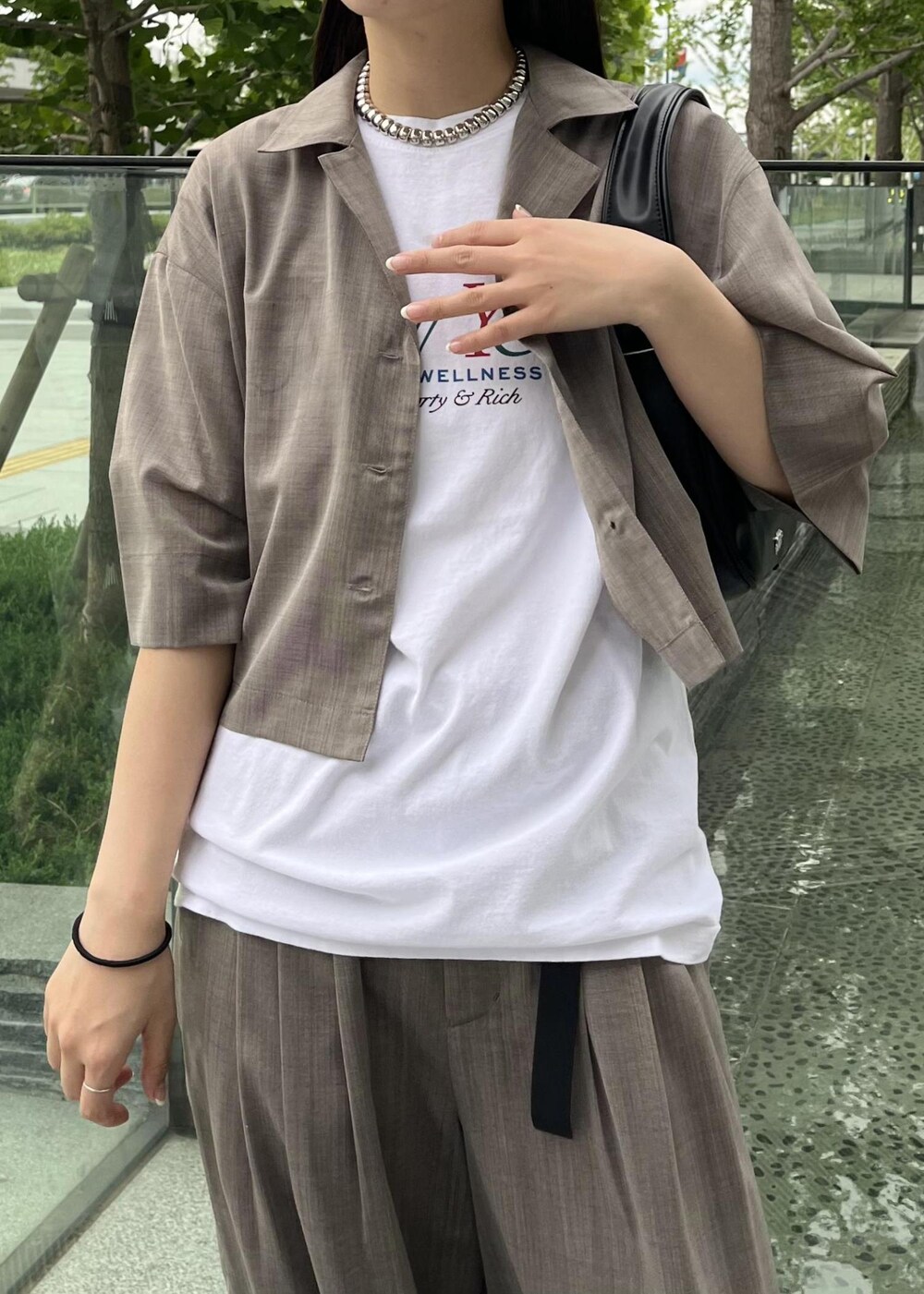 ベージュ系のサンダル、ブラック系のハンドバッグ、ベージュ系のスラックスを着用したレディースの夏コーディネートの3枚目の写真