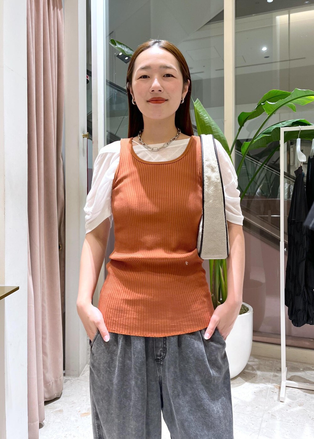 ホワイト系のハンドバッグ、ブラック系のデニムパンツを着用したレディースの夏コーディネートの4枚目の写真