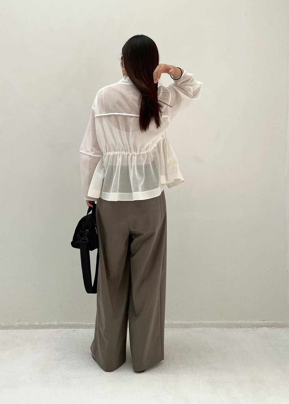 グレー系のスラックス、ホワイト系のカーディガン/ボレロを着用したレディースの春コーディネートの3枚目の写真