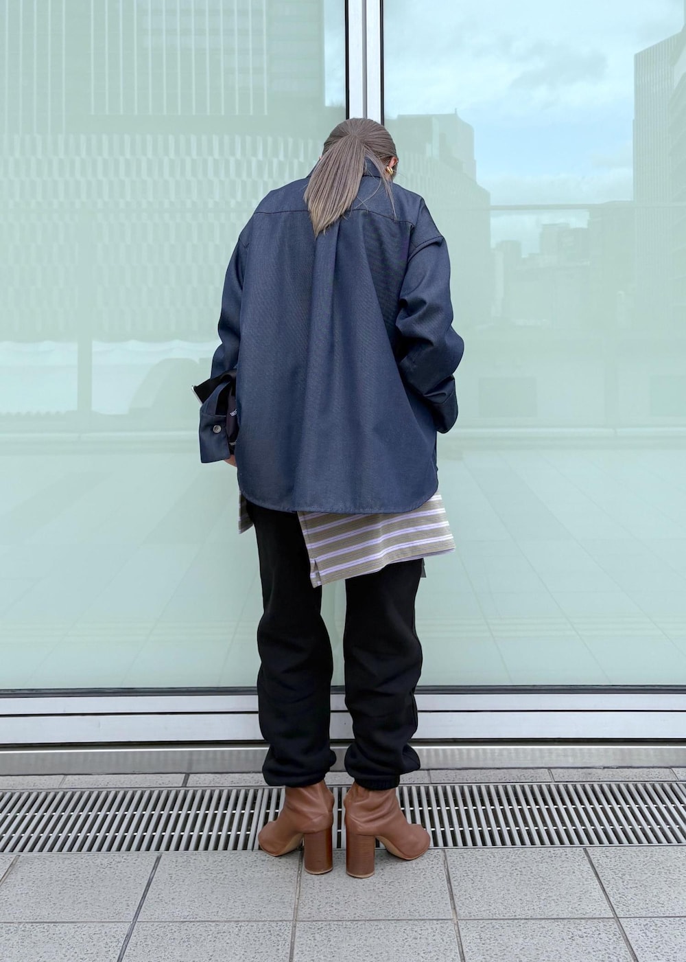 ブルー系のブルゾン、ブラック系のトートバッグ、パープル系のポロシャツを着用したレディースの冬コーディネートの4枚目の写真