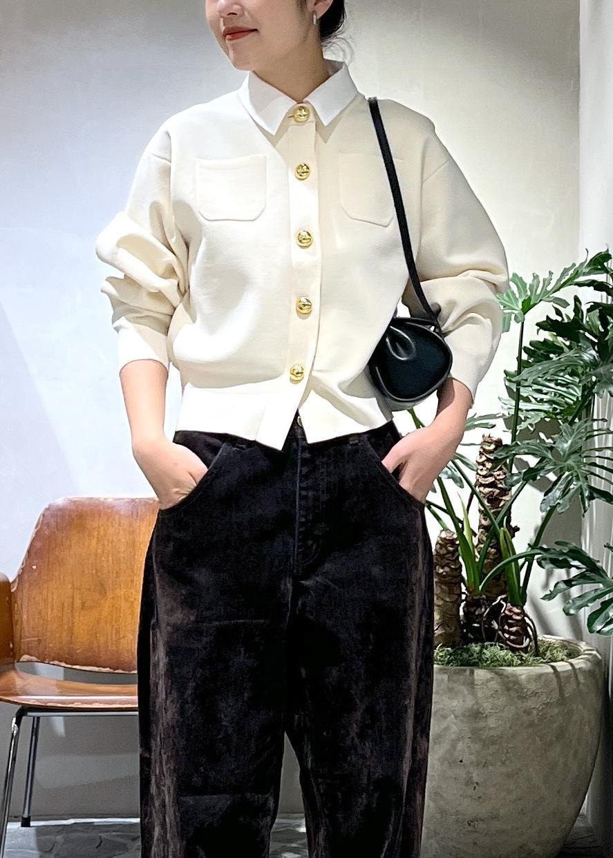 ブラック系のショルダーバッグ、ホワイト系のカーディガン/ボレロ、ブラウン系のデニムパンツを着用したレディースの冬コーディネートの4枚目の写真