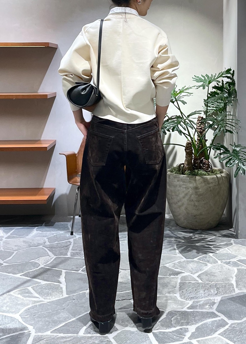 ブラック系のショルダーバッグ、ホワイト系のカーディガン/ボレロ、ブラウン系のデニムパンツを着用したレディースの冬コーディネートの3枚目の写真