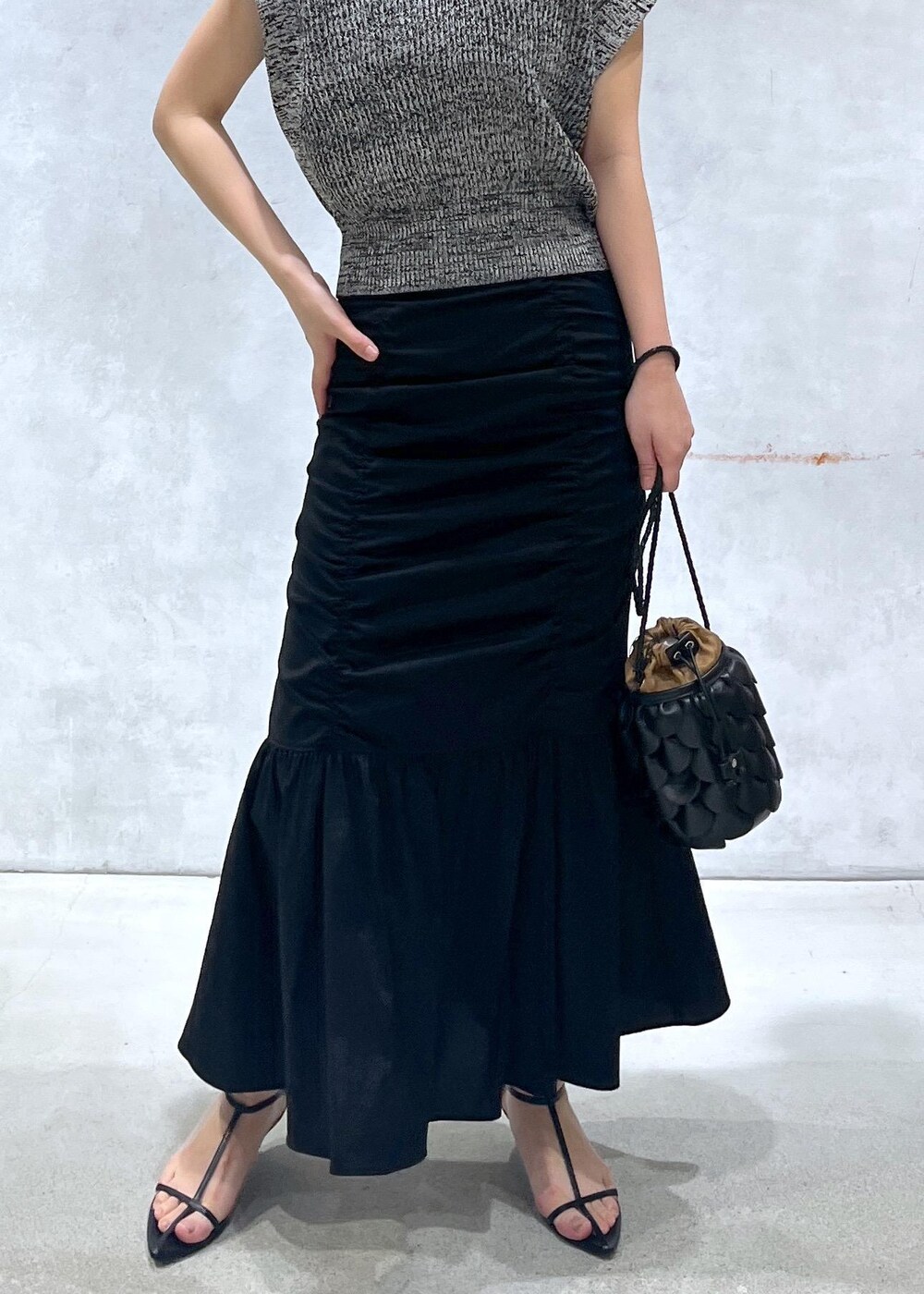 ブラック系のサンダル、ブラック系のスカート、ブラック系のベストを着用したレディースの春コーディネートの5枚目の写真