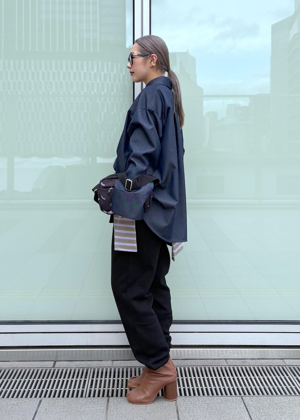 ブルー系のブルゾン、ブラック系のトートバッグ、パープル系のポロシャツを着用したレディースの冬コーディネートの3枚目の写真