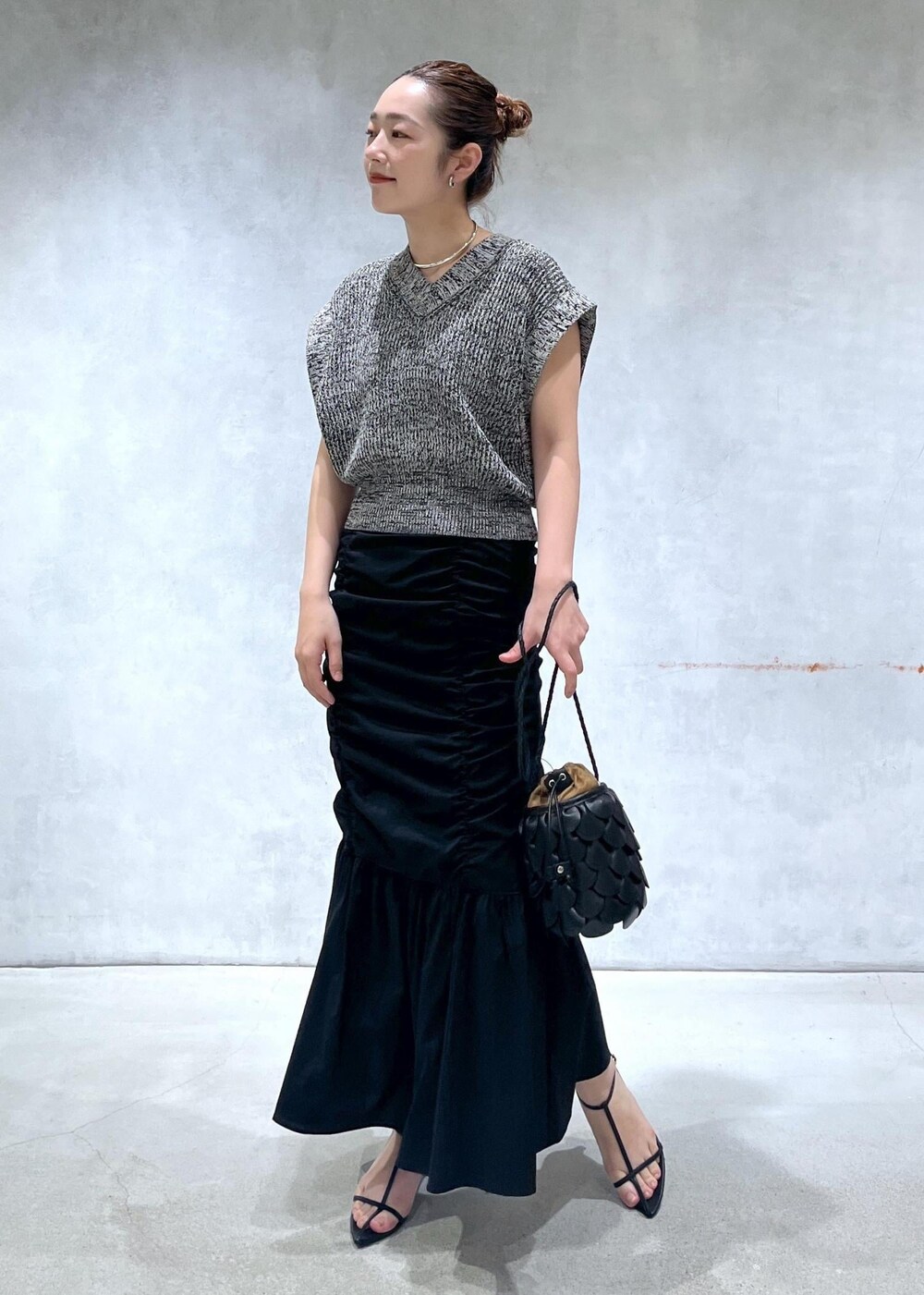 ブラック系のサンダル、ブラック系のスカート、ブラック系のベストを着用したレディースの春コーディネートの2枚目の写真