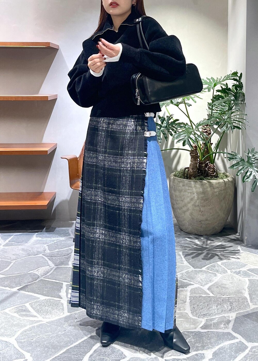 グレー系のスカート、ブラック系のブーツ、ブラック系のニット/セーターを着用したレディースの冬コーディネートの4枚目の写真