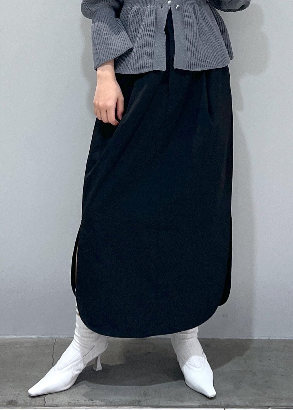 ホワイト系のパンプス、グレー系のカーディガン/ボレロ、ブラック系のスカートを着用したレディースの冬コーディネートの4枚目の写真