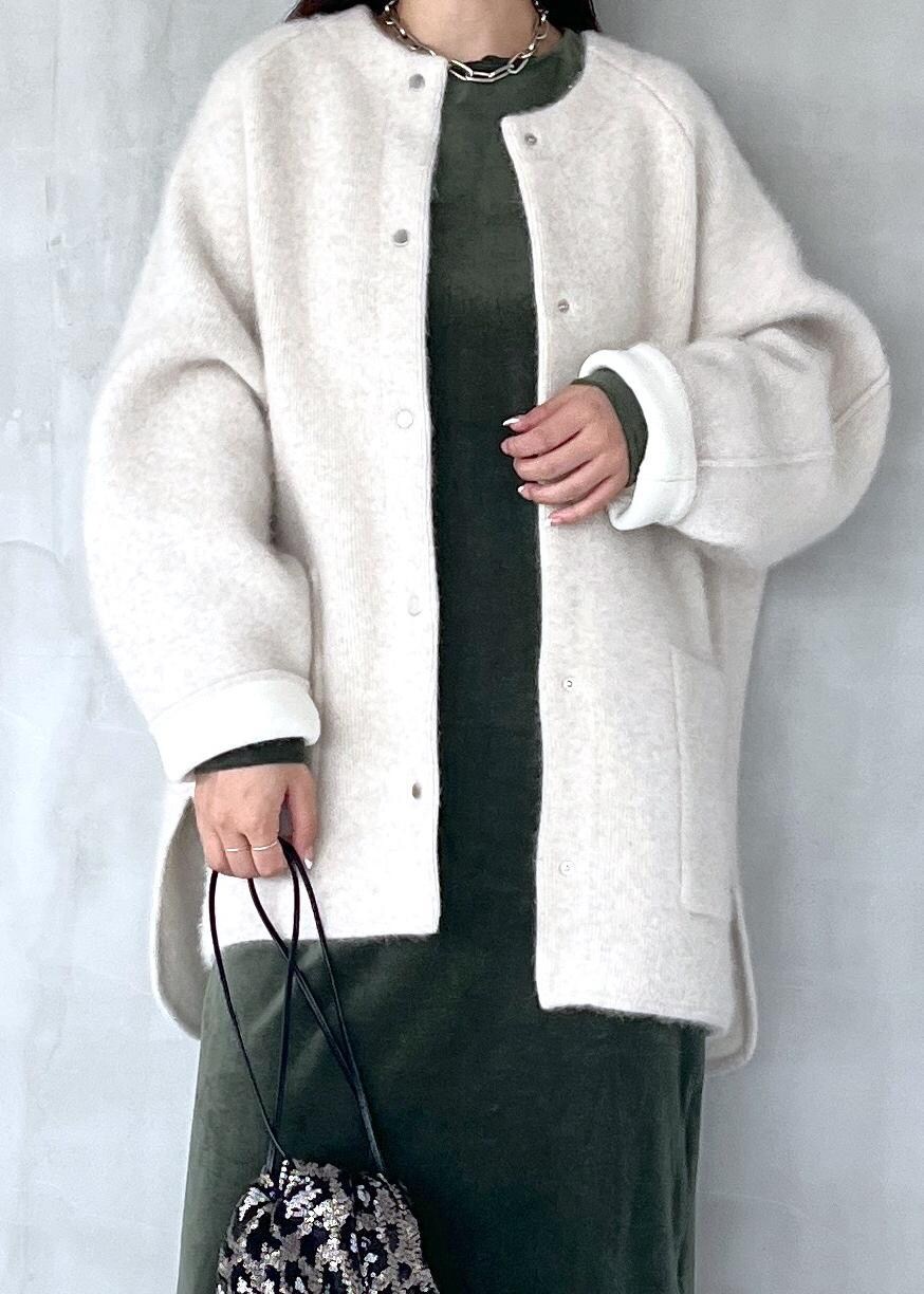 グリーン系のワンピース、ブラック系のブーツ、ホワイト系のカーディガン/ボレロを着用したレディースの秋コーディネートの4枚目の写真