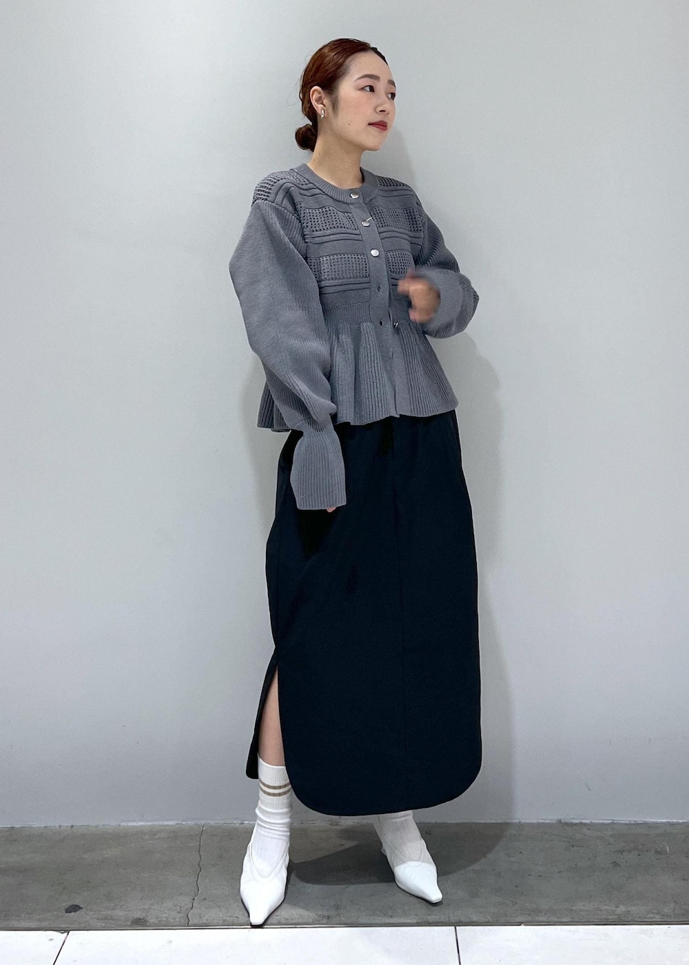 ホワイト系のパンプス、グレー系のカーディガン/ボレロ、ブラック系のスカートを着用したレディースの冬コーディネートの2枚目の写真