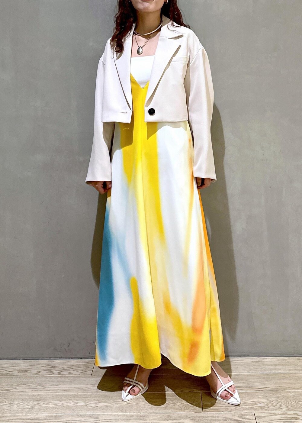 ホワイト系のサンダル、イエロー系のワンピース、ホワイト系のテーラードジャケットを着用したレディースの春コーディネートの4枚目の写真