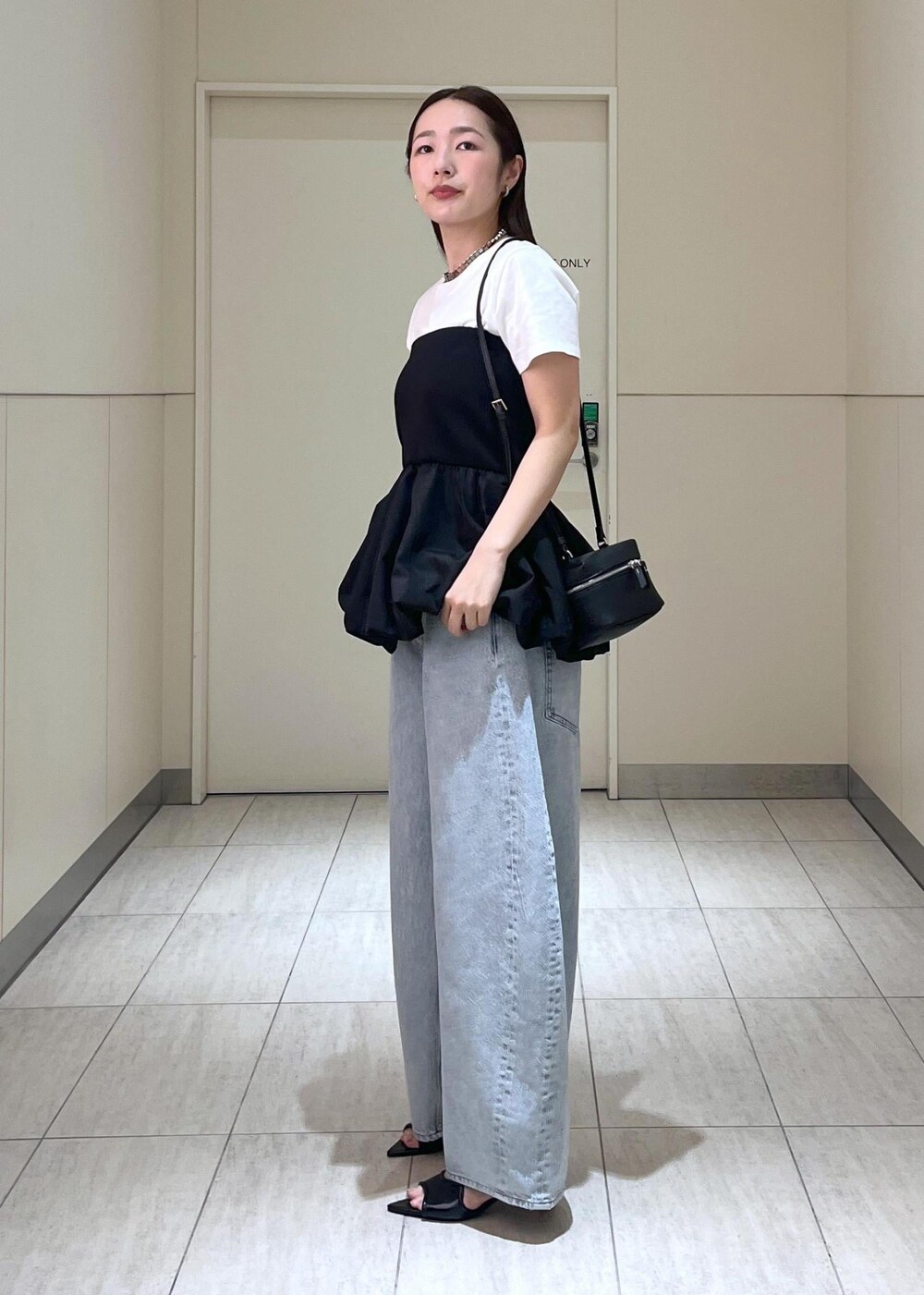 ブラック系のサンダル、ブルー系のデニムパンツ、ブラック系のTシャツ/カットソーを着用したレディースの春コーディネートの2枚目の写真