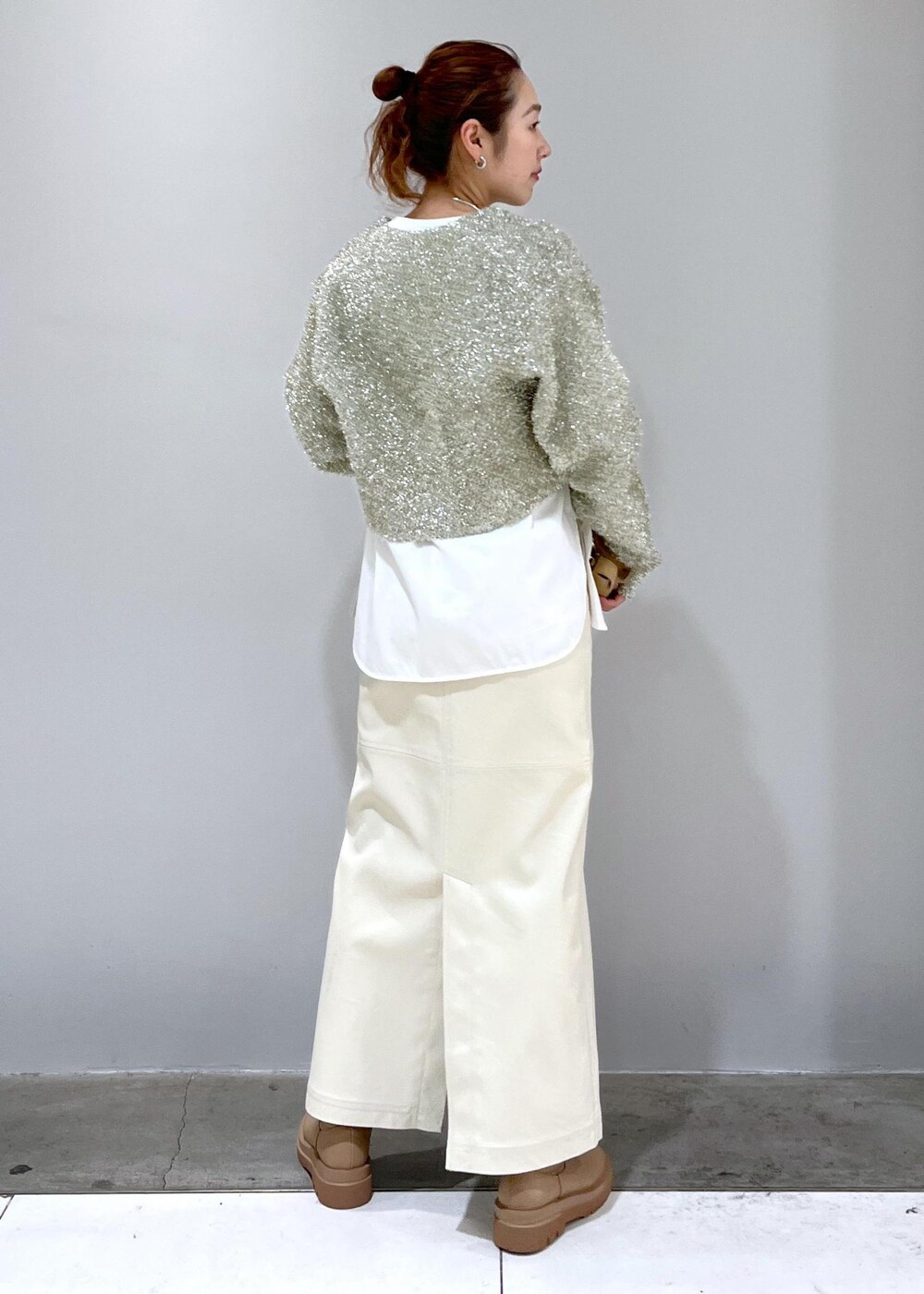 ホワイト系のスカート、ベージュ系のブーツ、ホワイト系のTシャツ/カットソーを着用したレディースの冬コーディネートの2枚目の写真