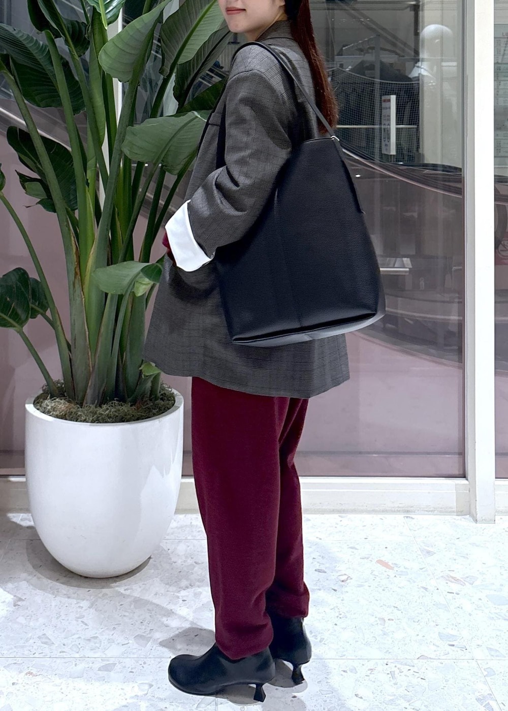 ブラック系のショルダーバッグ、ホワイト系のシャツ/ブラウス、ブラック系のブーツを着用したレディースの秋コーディネートの3枚目の写真