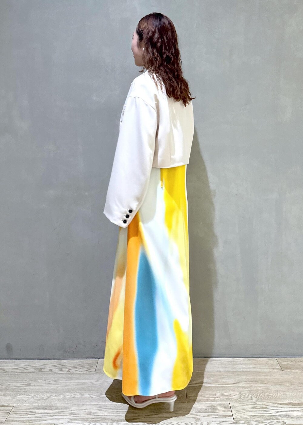 ホワイト系のサンダル、イエロー系のワンピース、ホワイト系のテーラードジャケットを着用したレディースの春コーディネートの2枚目の写真