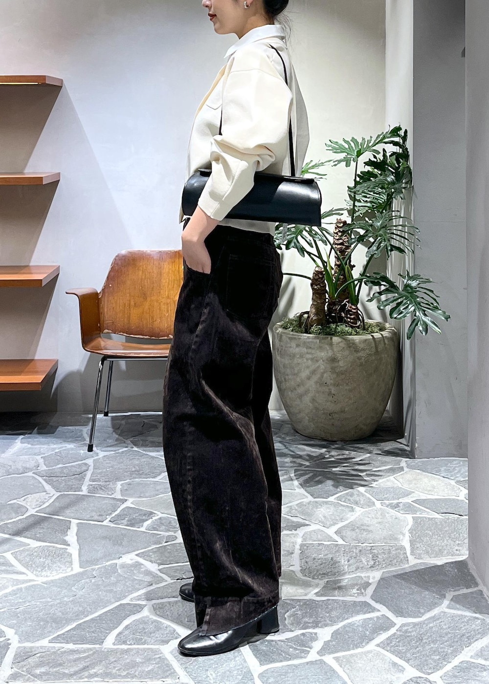 ブラック系のショルダーバッグ、ホワイト系のカーディガン/ボレロ、ブラウン系のデニムパンツを着用したレディースの冬コーディネートの2枚目の写真