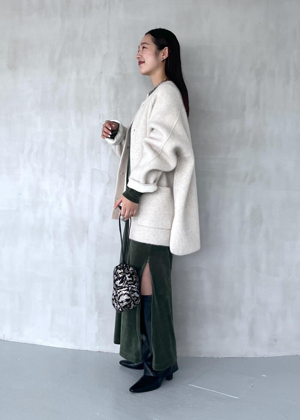 グリーン系のワンピース、ブラック系のブーツ、ホワイト系のカーディガン/ボレロを着用したレディースの秋コーディネートの2枚目の写真