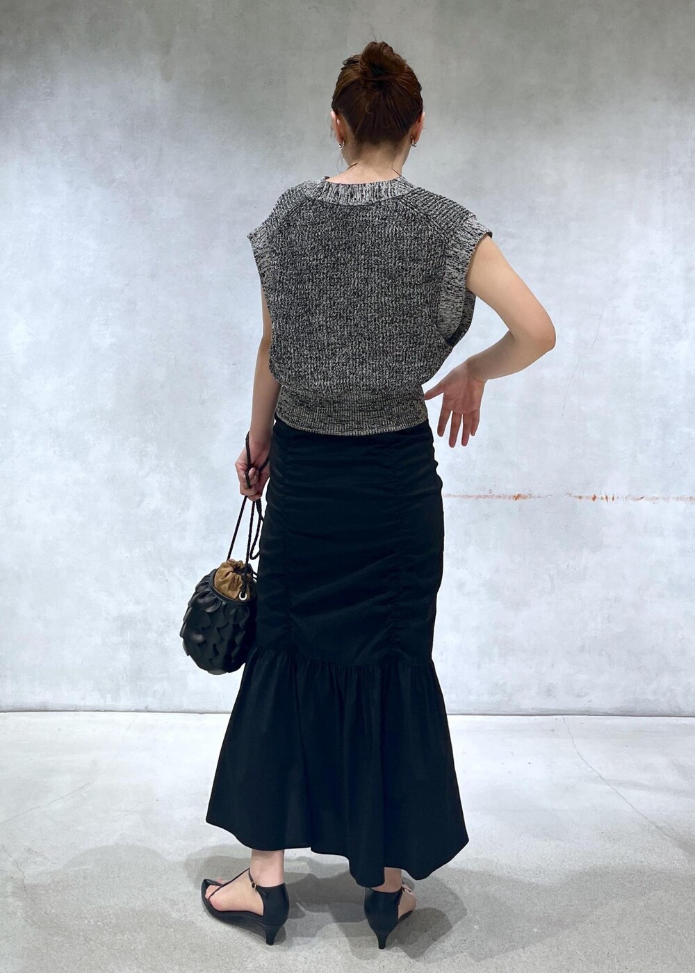 ブラック系のサンダル、ブラック系のスカート、ブラック系のベストを着用したレディースの春コーディネートの3枚目の写真