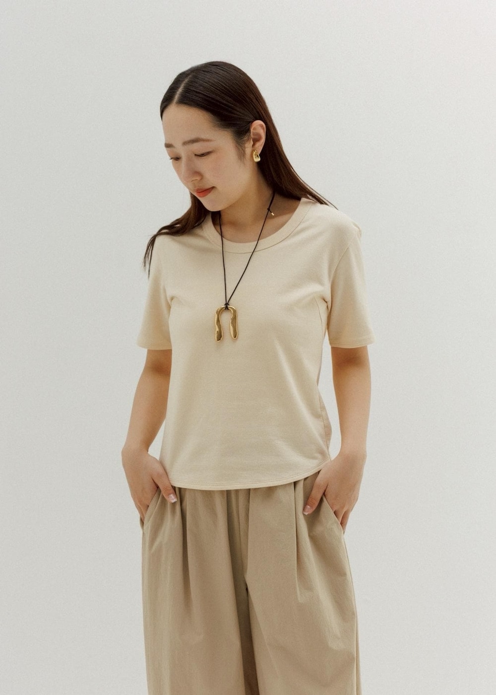 ブラック系のサンダル、ベージュ系のその他パンツ、ベージュ系のTシャツ/カットソーを着用したレディースの春コーディネートの2枚目の写真