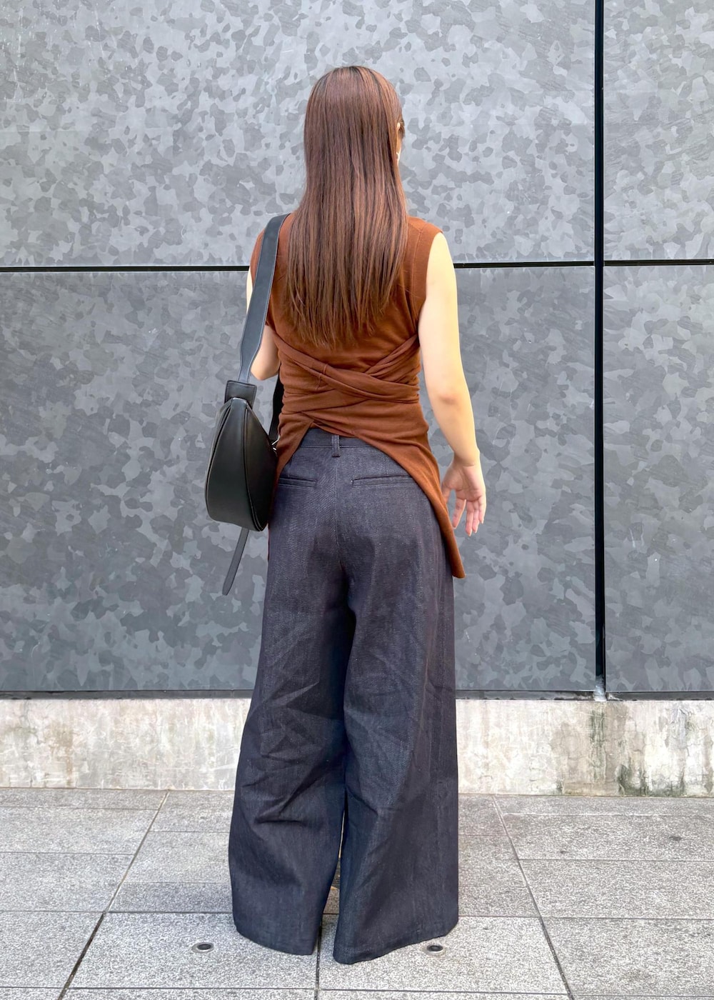 ブラウン系のニット/セーター、ブルー系のデニムパンツ、ブラック系のショルダーバッグを着用したレディースの夏コーディネートの2枚目の写真