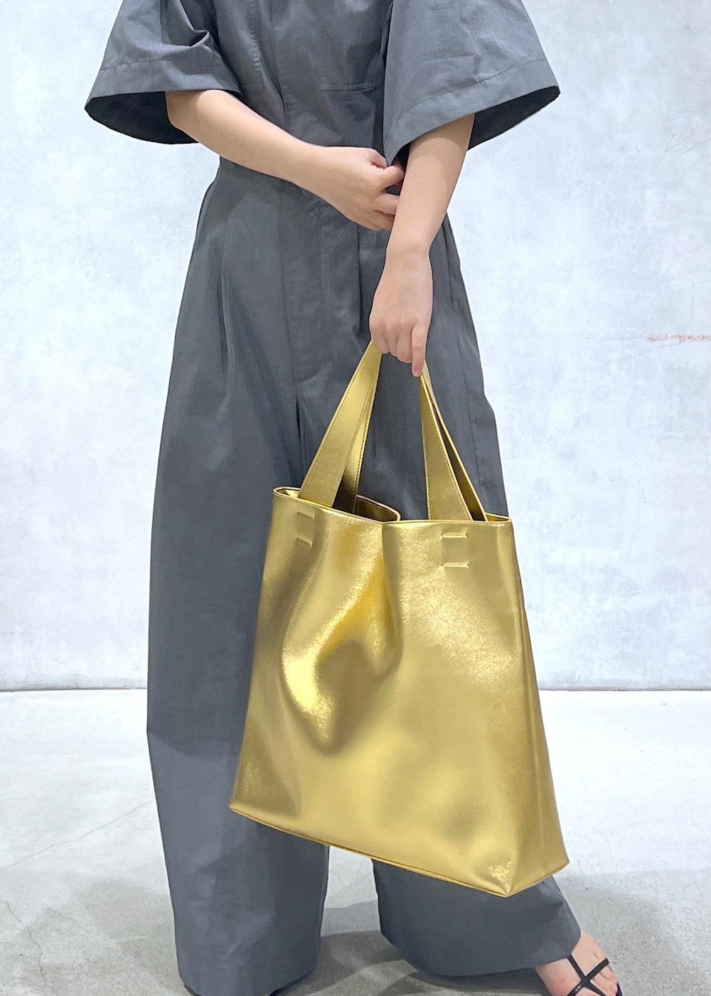 ブラック系のサンダル、ゴールド系のトートバッグ、グレー系のつなぎ/オールインワンを着用したレディースの春コーディネートの5枚目の写真