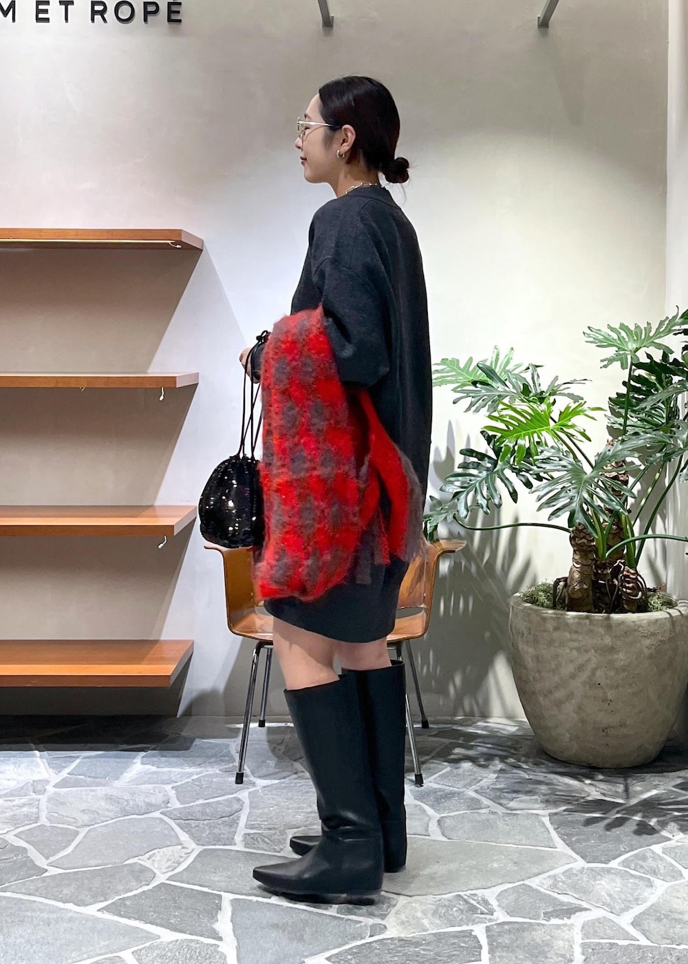 ブラック系のブーツ、グレー系のニット/セーター、ブラック系のハンドバッグを着用したレディースの秋コーディネートの2枚目の写真