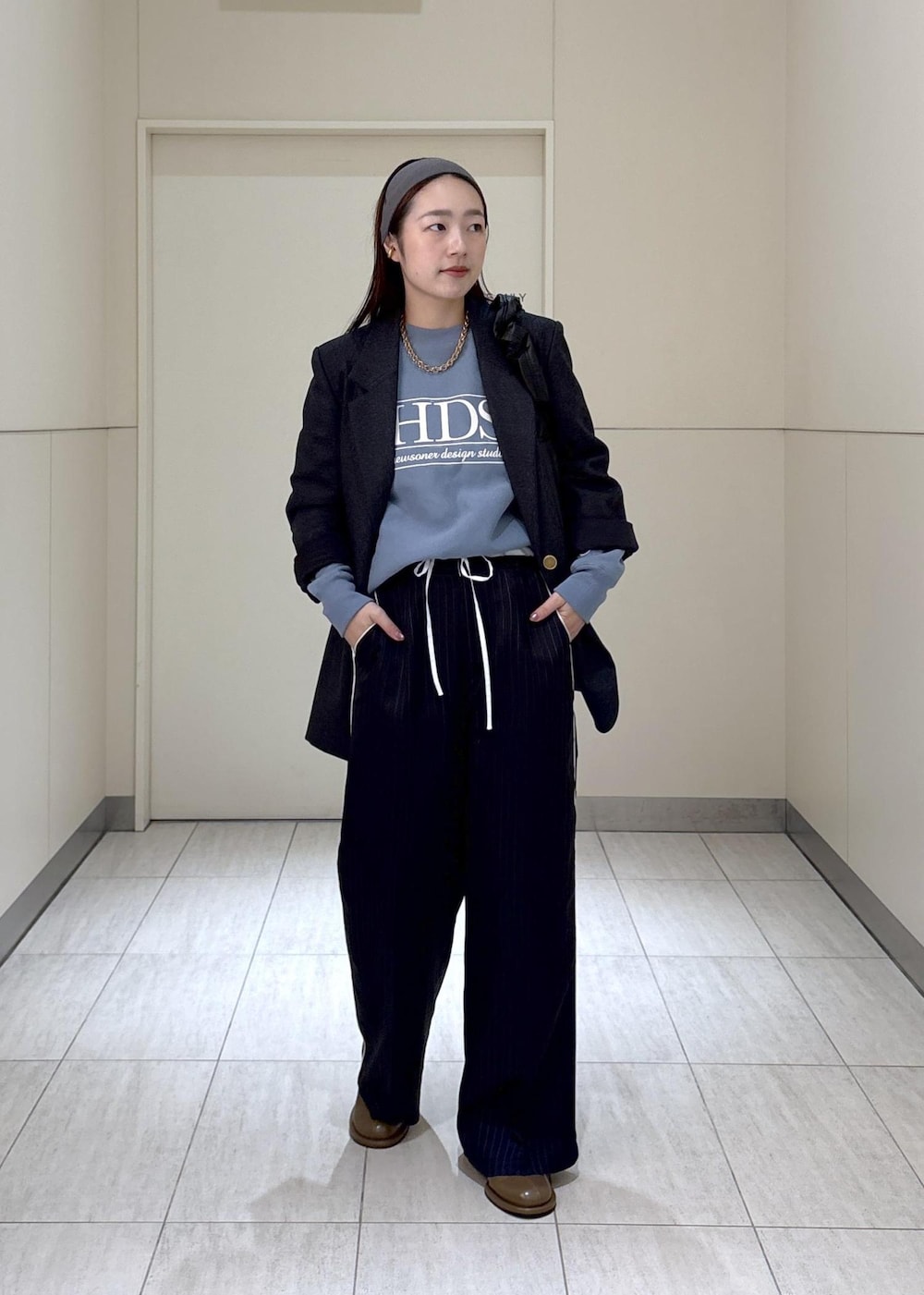 ブルー系のスウェット、ブラウン系のサンダル、グレー系のテーラードジャケットを着用したレディースの秋コーディネートの2枚目の写真