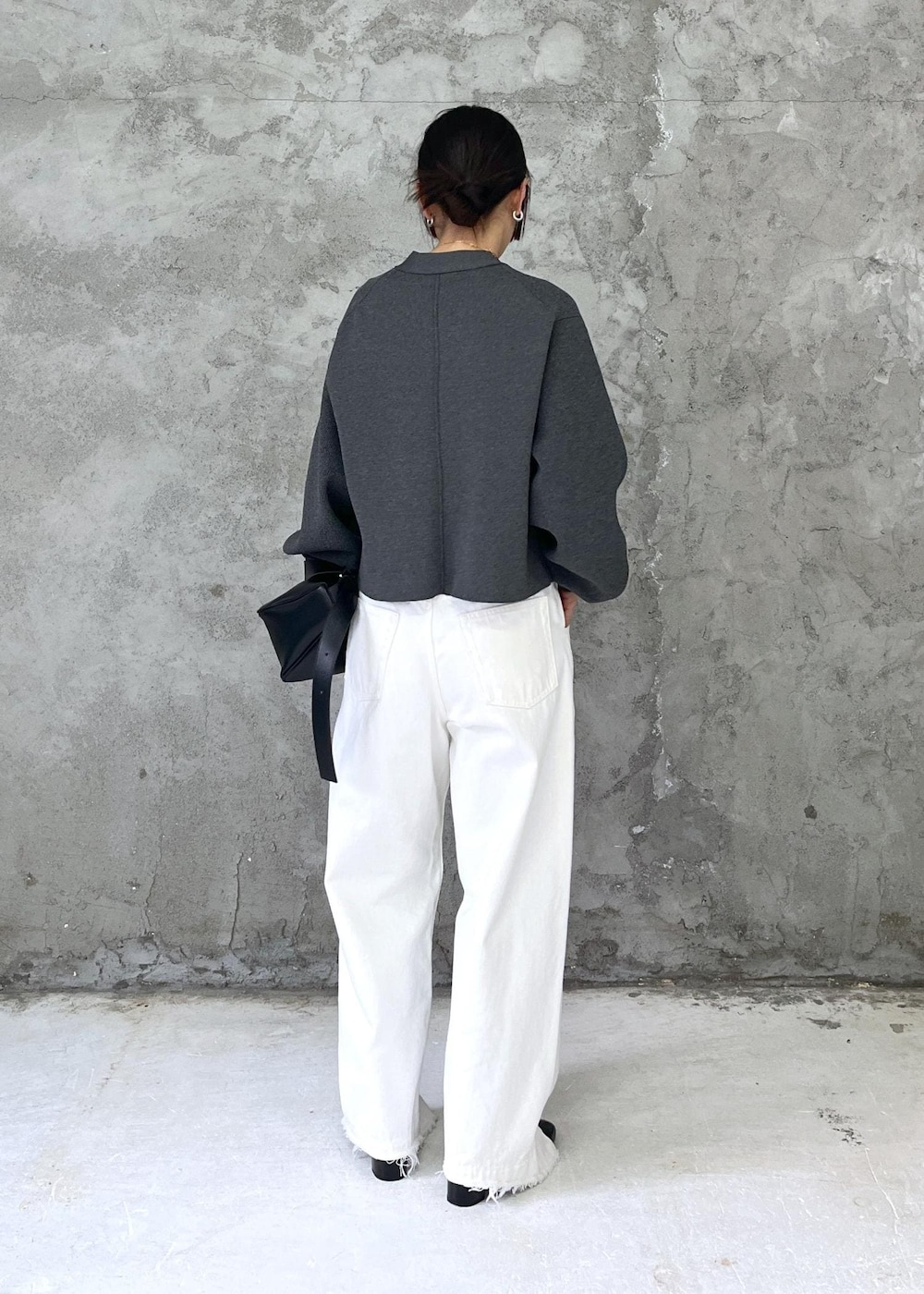 ブラック系のパンプス、ホワイト系のデニムパンツ、グレー系のカーディガン/ボレロを着用したレディースの冬コーディネートの2枚目の写真