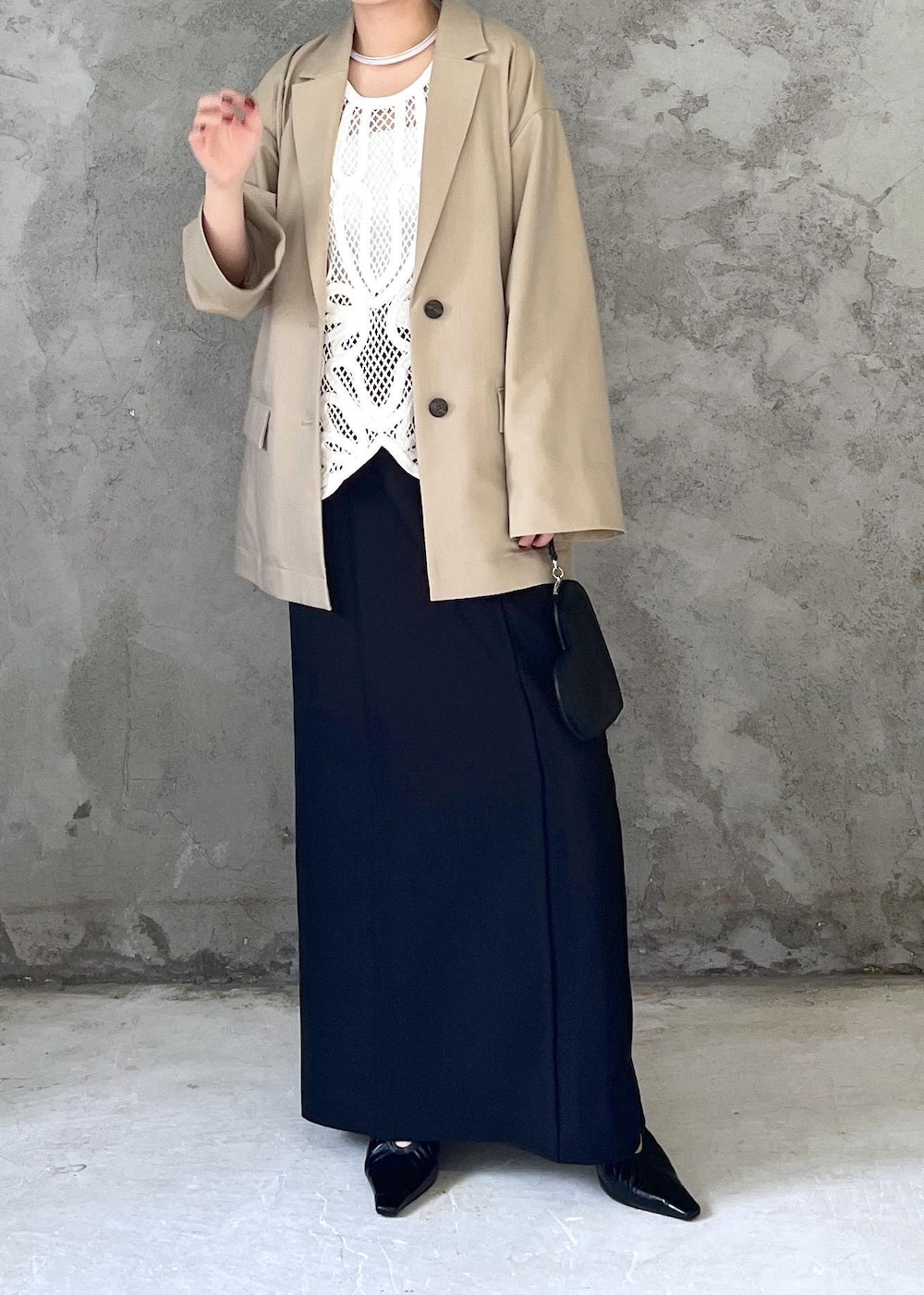 ブラック系のクラッチバッグ、ホワイト系のベスト、ベージュ系のテーラードジャケットを着用したレディースの冬コーディネートの3枚目の写真