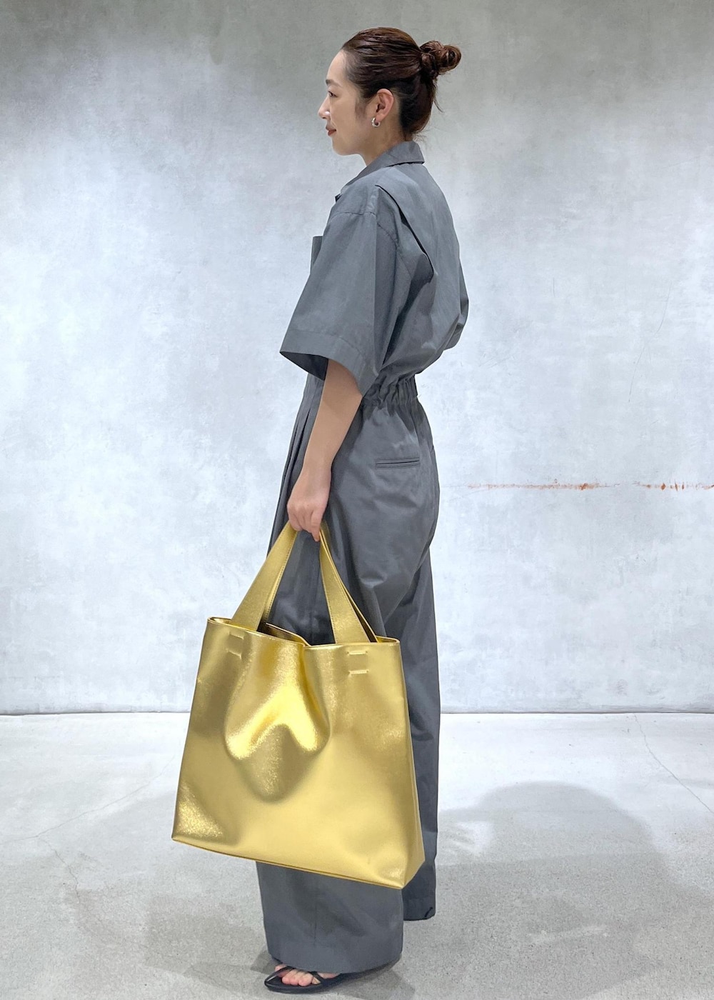 ブラック系のサンダル、ゴールド系のトートバッグ、グレー系のつなぎ/オールインワンを着用したレディースの春コーディネートの2枚目の写真