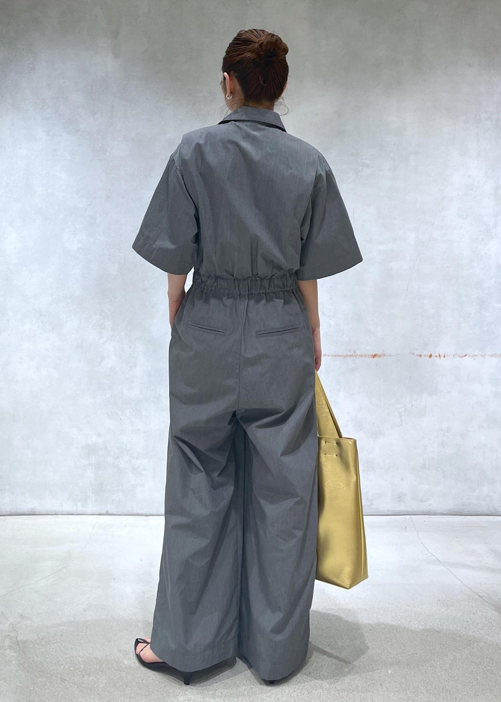 ブラック系のサンダル、ゴールド系のトートバッグ、グレー系のつなぎ/オールインワンを着用したレディースの春コーディネートの3枚目の写真