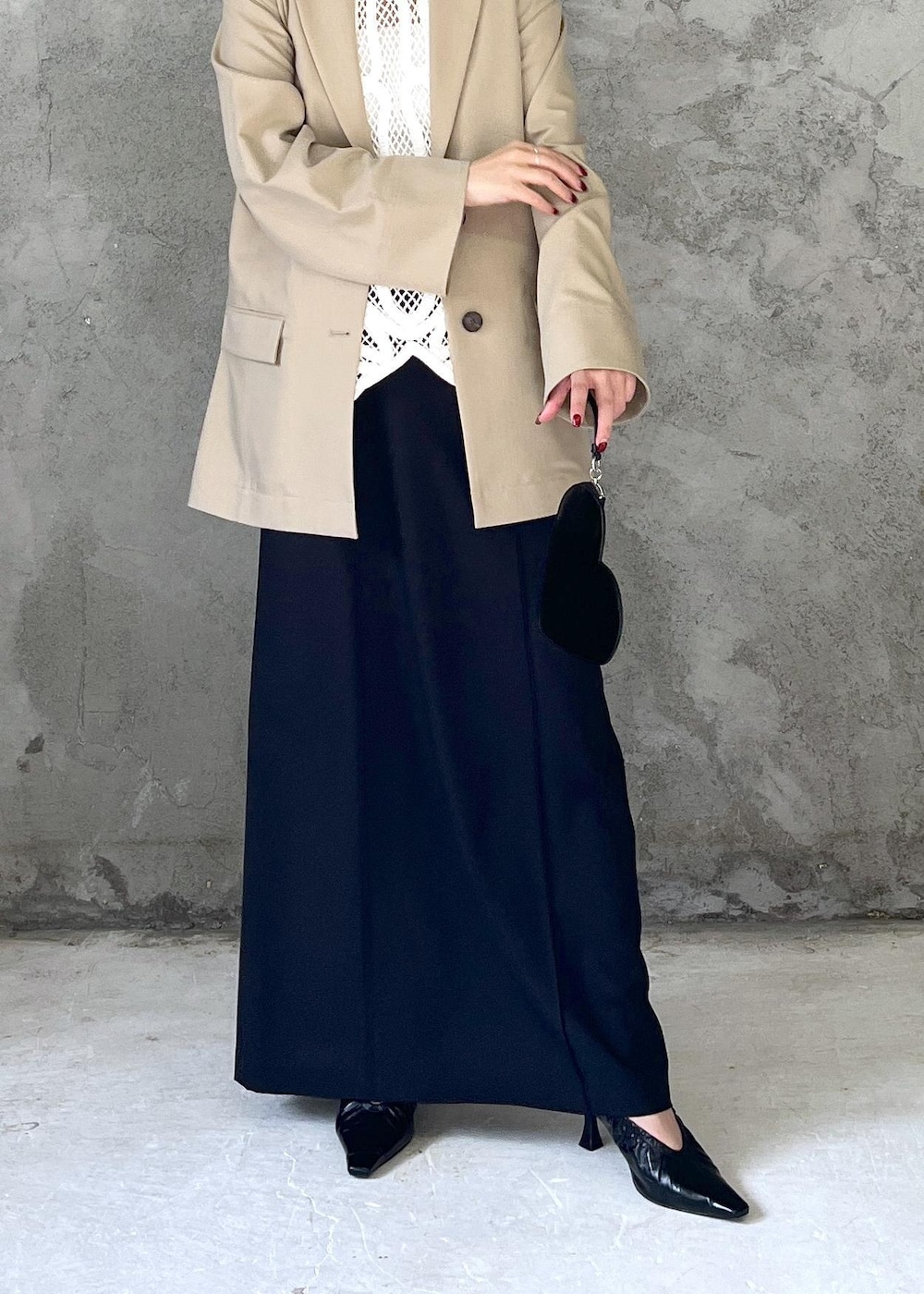 ブラック系のクラッチバッグ、ホワイト系のベスト、ベージュ系のテーラードジャケットを着用したレディースの冬コーディネートの4枚目の写真