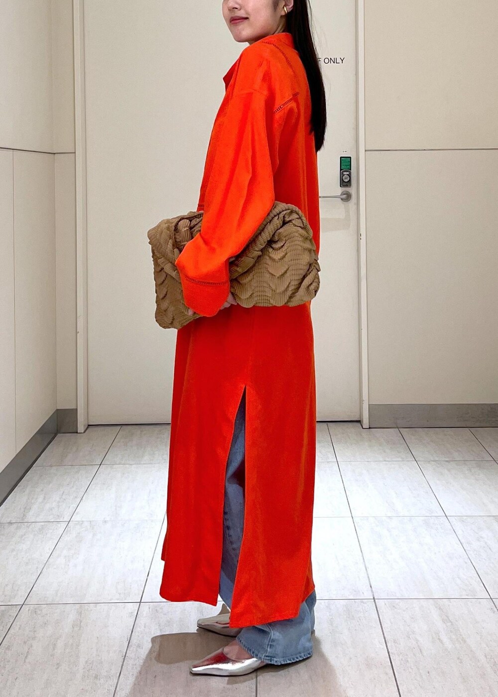 ブルー系のデニムパンツ、レッド系のワンピース、シルバー系のサンダルを着用したレディースの春コーディネートの3枚目の写真