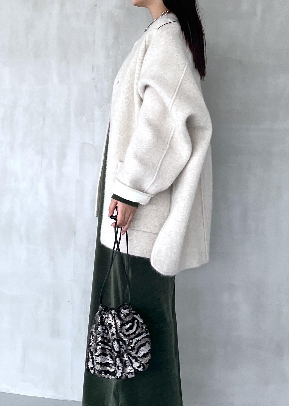 グリーン系のワンピース、ブラック系のブーツ、ホワイト系のカーディガン/ボレロを着用したレディースの秋コーディネートの5枚目の写真