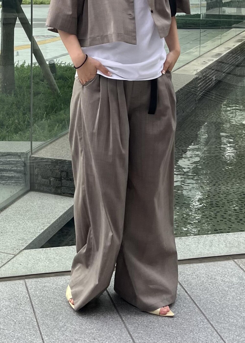 ベージュ系のサンダル、ブラック系のハンドバッグ、ベージュ系のスラックスを着用したレディースの夏コーディネートの4枚目の写真